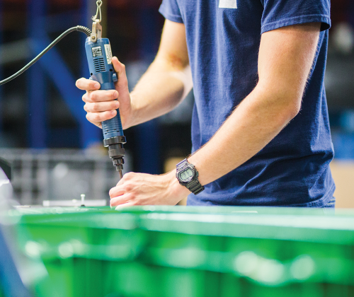 A man works with a tool in a factory.